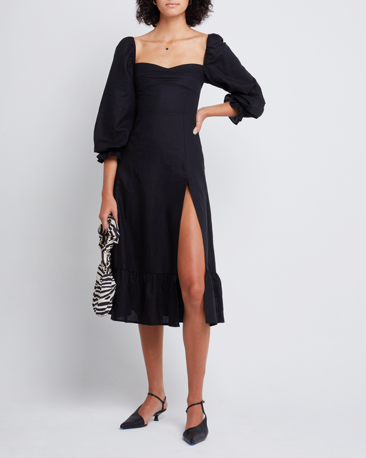 First image of Aubrey Midi Dress, a black midi dress, long sleeves, puff sleeves, sweetheart neckline, side slit