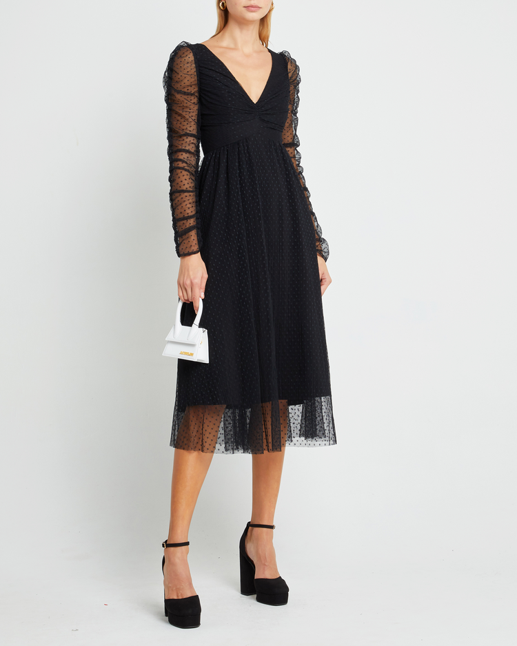 First image of Daisy Dress, a black wedding guest dress with sheer long sleeves, v-neckline, ruched gathered bust detail, cinched waist, lining, dotted mesh fabric, and back zipper