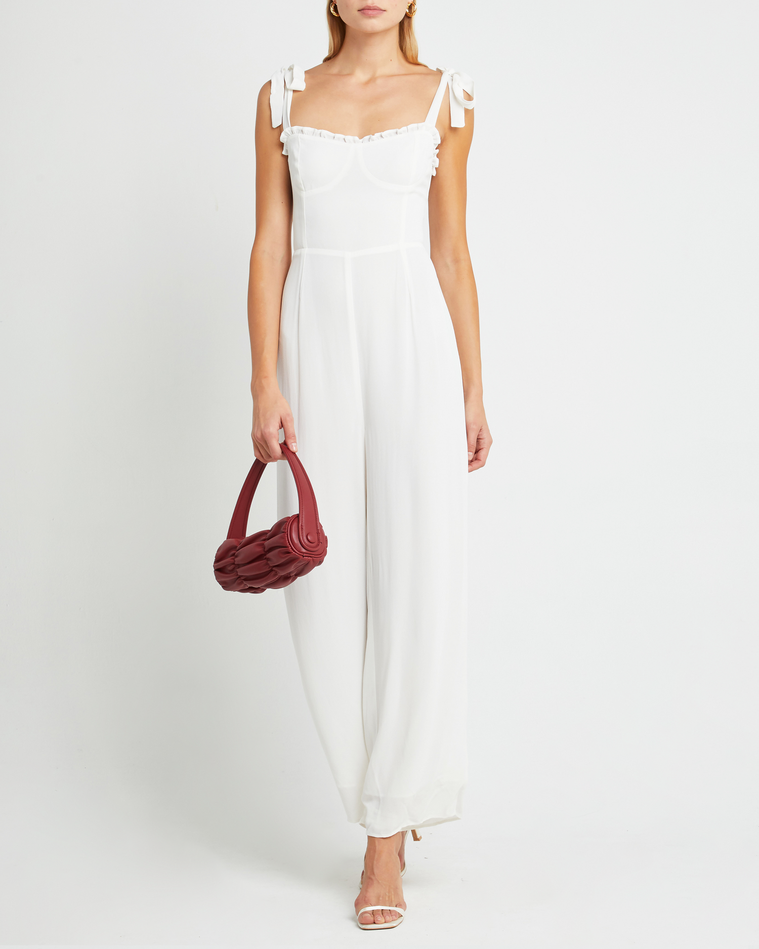 First image of Blair Jumpsuit, a white jumpsuit with straight-leg lined pants, adjustable tie straps, cup detail, neckline ruffles, and a back zipper